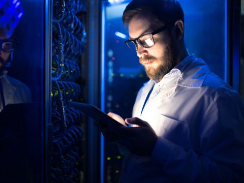 Men working in a datacentre looking at mobile device