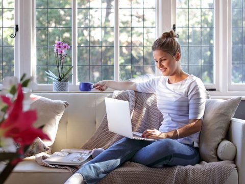 Woman working on a laptop sitting on a sofa